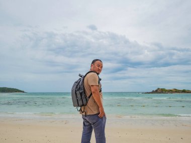 Asyalı şişman backpacker tatil zamanı tribünde kullanım cep telefonu güzel gökyüzü ile pastoral plaj üzerinde iken. Samae San Adası Tayland. Yaz konsepti.