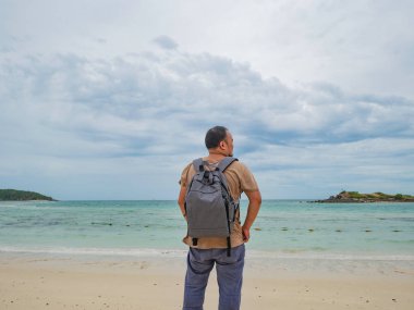 Asyalı şişman backpacker tatil zamanı tribünde kullanım cep telefonu güzel gökyüzü ile pastoral plaj üzerinde iken. Samae San Adası Tayland. Yaz konsepti.