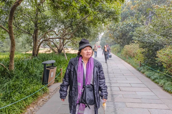 Old asian women traveler walk in the xihu lake(west lake) park in hangzhou city china