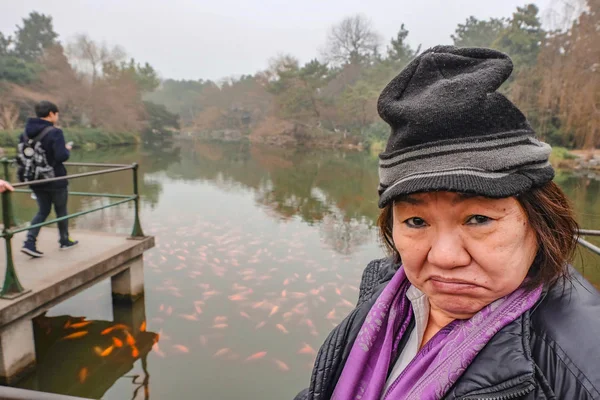 Happy old asian women traveler make a funny face in the xihu lake(west lake) park in hangzhou china