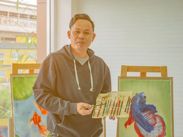 ハンサムな若いアジア人または水カラー アーティスト教室 魚の概念でペイント ブラシを使用する方法を教える — ストック写真