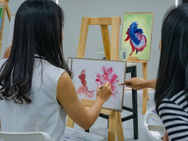 Two young asian woman artist dawning while useing ideas to think and create the best artwork together,fish concept