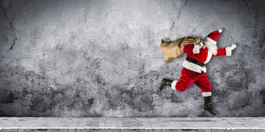geç Noel Baba acele geleneksel kırmızı beyaz kostüm ve çanta dolu sunar soyut komik Noel atlama koşma xmas beton arka plan kopya alanı ile