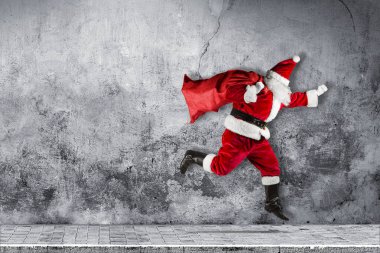 geç Noel Baba acele geleneksel kırmızı beyaz kostüm ve çanta dolu sunar soyut komik Noel atlama koşma xmas beton arka plan kopya alanı ile