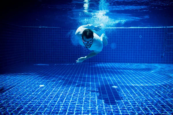 young man with sunglasses enjoying the swimming pool abstract summer fun underwater swimming jump diving background