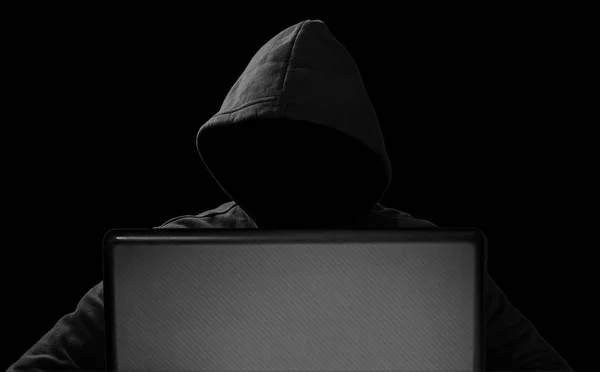 Hacker con máscara brillante detrás de portátil portátil en frente de isol — Foto de Stock