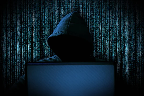 Hacker with red glowing mask behind notebook laptop in front of — Stock Photo, Image