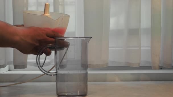 El jugo se vierte del extractor de jugo en una jarra . — Vídeo de stock