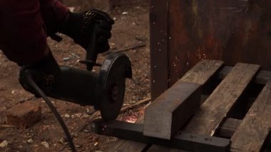 Metal kesme için el ile makine çalışır. Taraflara kıvılcımlar. Metal kesme işlemi çalışma. İşçi bir detay testereleri. Hızlı bir şekilde disk döner, parlak kıvılcımlar taraflar dağılmış.