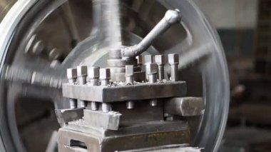 Makine bir detay işler. Makinenin büyük metal mekanizması döner. Ayrıntılar somunlar, kolu görünür. Üretim süreci yakın çekim.