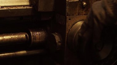 Vasıl belgili tanımlık makine mühendislik tesisi işlemi çalışma. Erkek makine operatörünün çalışan işlemi, bir kumanda kolu çevirerek düzenlemektedir. Detay keskinleşmiş olduğunu. Metal tıraş uçar. Alt görünümü.