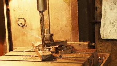 Vasıl belgili tanımlık makine mühendislik tesisi işlemi çalışma. Delme sırasında metal tıraş ortaya çıkması. Yakındaki çizimler asmak.