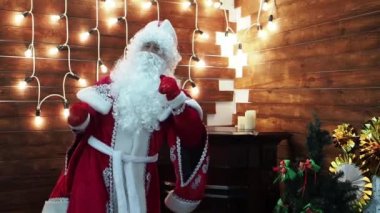 Babası Frost Noel Baba dansları parlak çelenk arka planı. Novogodniyrozhdestvensky çocuk karakter fierily ve güzel dans ediyor.