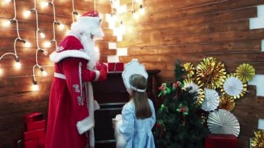 Küçük kız babası Frost Noel Baba hediye kutuları için Snegurochka sunar. Yeni yıl Noel karakter Rus geleneklerin bir şömine evde hediyeleri.