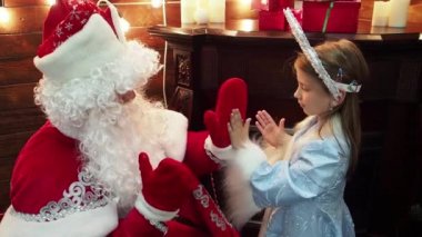 Babası Frost Noel Baba ve küçük kız Snegurochka avuç içi oynamak. Yeni yıl Noel masal karakterleri Rus geleneği oyun pat-a-pasta bir şömine ve köknar ağacı. Yakın çekim.