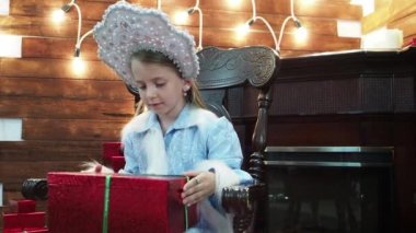 Küçük kız bir şömine yakın ahşap bir sandalyede oturuyor. Güzel güzel kız peri masalı yeni yıl'ın Noel karakter farklı partiler mühürlü hediyesi olarak görüyor. Küçük kar kraliçesi.