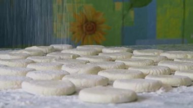 Bir tablo yarı bitmiş ürünler yalan üzerine. Yukarıdan un dökün. Yakın çekim. Un serpin yukarıda oluşturulan cheesecakes.