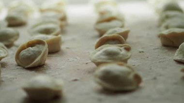 Çok fazla pelmeni var. Yarı bitmiş ürünler masanın üzerinde yatıyor. Kapat..