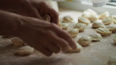 Yaşlı kadın Mantı bir masanın üzerine koyar. Yarı bitmiş ürünler bir masada yalan. Yakın çekim.