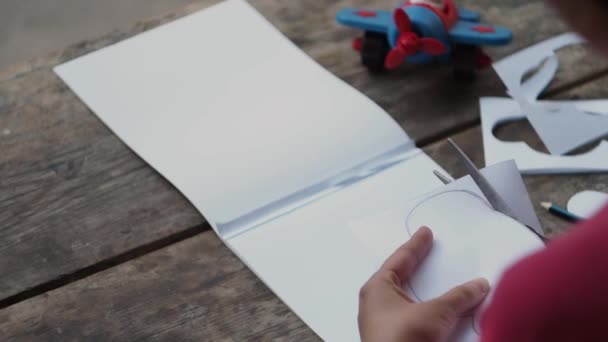 那个女人从纸上剪下一片云 用纸张进行创造性的工作 剪刀和儿童玩具飞机在飞行员附近 闭上你的嘴复古风格 — 图库视频影像