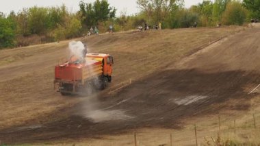 Adam bir hortum yüksekliği yeryüzünde su. Arazi yarışı için rota hazırlanması. Adam makine üzerinde yüklü. Yukarıdan seyirci görünüyor.