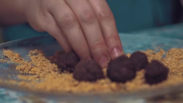 Дівчина формує шоколадні кульки з порошком. крупним планом . — стокове відео