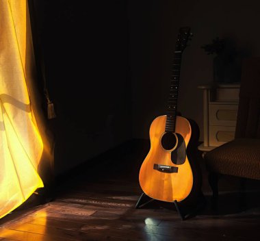 Akustik İspanyol gitar bir stand bir perde arkasından gelen parlak ışık ile karanlık bir odada moody gölgeler içinde
