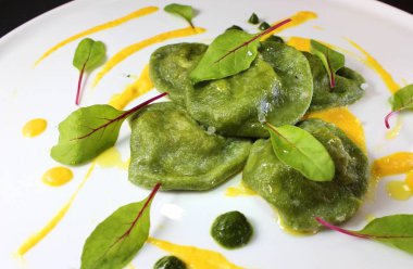 Ispanak ravioli mantar duxelles ile kabak sos ile ve kırmızı ven kuzukulağı ile süslenmiş