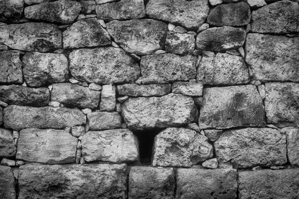 Old rustic stone wall in black and white with varied and sizes and textures