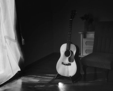 Akustik İspanyol gitar bir stand bir perde arkasından gelen parlak ışık ile karanlık bir odada moody gölgeler içinde siyah ve beyaz fotoğraf