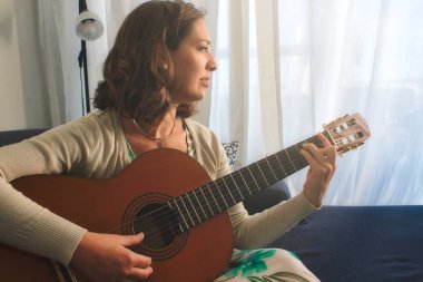 İspanyol gitar çalan evde bir kanepede oturan çekici genç kadın