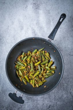 Hint baharat hazır garnitür olarak servis içinde kızarmış bir wok içinde bamya adet dilimlenmiş. Karanlık bir köri olduğunu gri arka plan kullanılır.