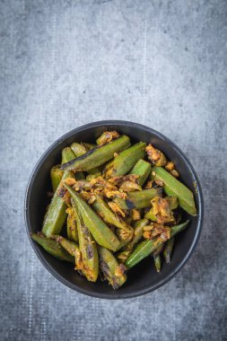 Vejeteryan bamya köri bir küçük siyah kase üstten görünüm ile vurdu. Hint kızarmış bamya köri Merkezi. Gri bir arka plan ile Bhindi köri. 