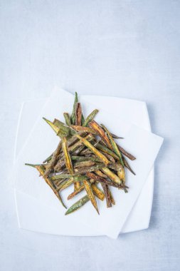 Derin yağda kızartılmış beyaz kare tabak ve beyaz bir arka plan üzerinde bamya. Kızarmış bhindi Indina baharatlar ile. Yeşil kızarmış bamya.