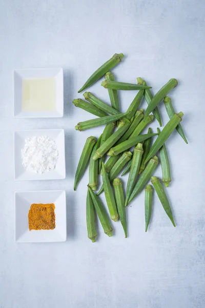 Flour, Indian spices, oil and uncooked raw okra. Uncooked bhindi. Uncooked Indian lady fingers. Healthy Indian bhindi recipe ingredients.