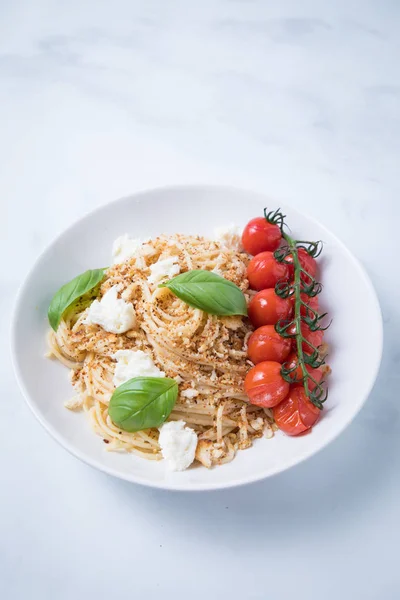 スパゲッティ パンくずリスト チェリー トマト 新鮮なバジルの葉と白い背景の白いプレートにバジリコのローストつるベジタリアン簡単イタリアン パスタ — ストック写真
