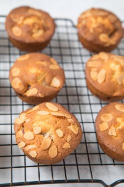 Bir fırın tepsisinde kiraz badem kekler kapatın. Beyaz arka plan. Altın muffins üstüne flaked badem.