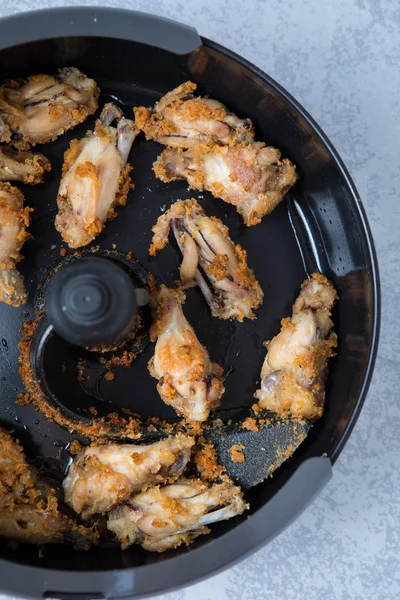 Air fried chicken wings in an air fryer. Close up of tasty air fried chicken wings on a grey background.