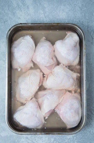 出したという鶏太股トレイと灰色の背景上の平面図です 皮をつけたまま塩水漬け鶏肉 — ストック写真