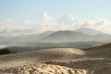 Dunes dağlar içinde belgili tanımlık geçmiş. Joaquina'nın plaj, mavi gökyüzü bulutlu. Florianpolis, Santa Catarina / Brezilya