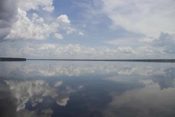 A natural mirror. Sky and clouds reflected on the river. Travelling through amazon by boat. \'Rio Negro\' river, Amazon / Brazil