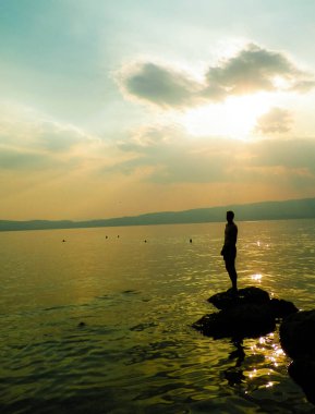 Ochrid Gölü üzerinde gün batımı. Güneşin Ochrid Gölü 'nün güzel sularına yansıması ve rahat turistler sahilde iyi vakit geçirsin. Seyahat ve güzellik doğada var..
