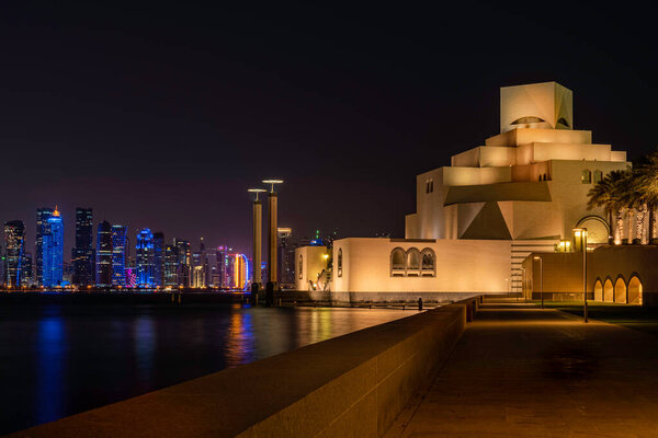 Doha, Qatar - August 26, 2020: Museum of Islamic Art building at Doha, Qatar, with night skyline background and bay water reflection