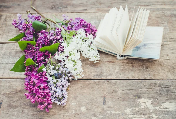 Lilac flowers and book on a wooden background