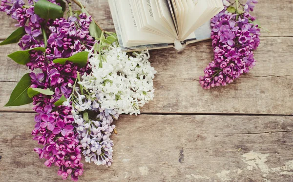 Lilac flowers and book on a wooden background
