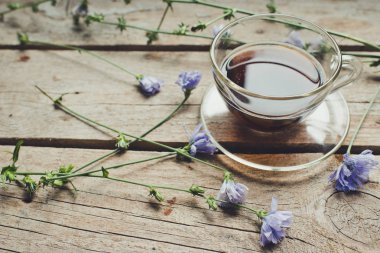 Ahşap bir masada hindiba içecek ve mavi hindiba çiçekleri ile Fincan