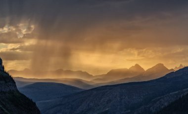 Günbatımı ve yağmur uzak dağların buzul Milli Parkı Montana, ABD üzerinde birleştirir. Bir yaz akşamı güneş yola gitmekten gördüm.