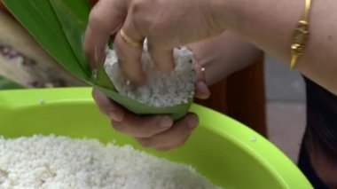 Yaşlı bir adam zongzi yapıyor, geleneksel bir Çin yemeği.