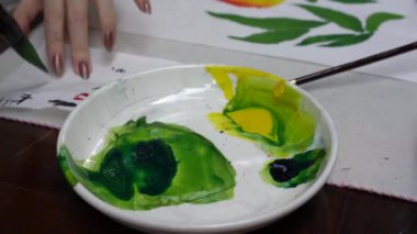 Bir ressam Çin tabloları yapıyor ve onları palete boyuyor.
