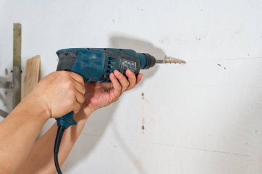 Bir işçi vurmalı matkapla duvarda delik açıyor.
